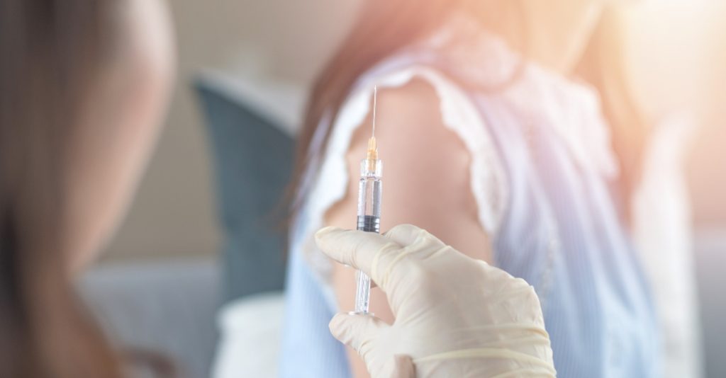 World immunization week and International HPV awareness day concept. Woman having vaccination for influenza or flu shot or HPV prevention with syringe by nurse or medical officer.